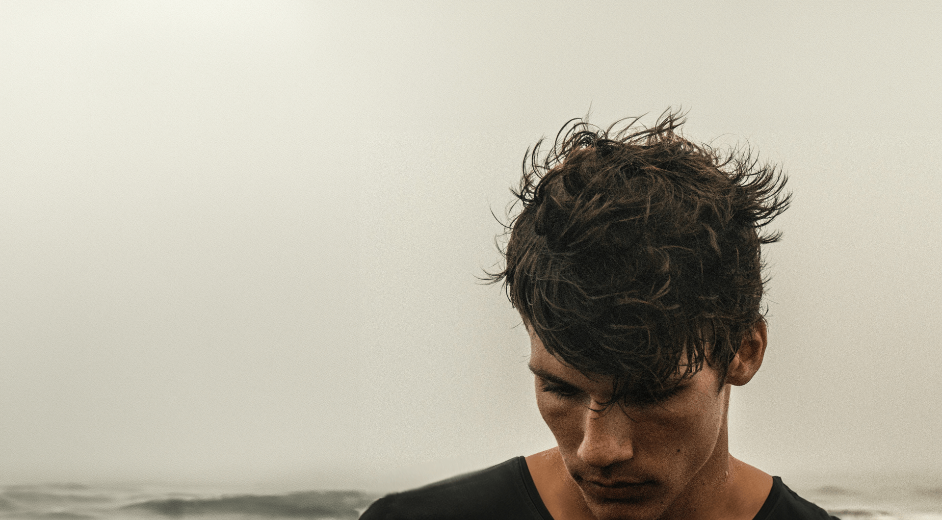 Muž na pláži s rozevlátými zdravými vlasy